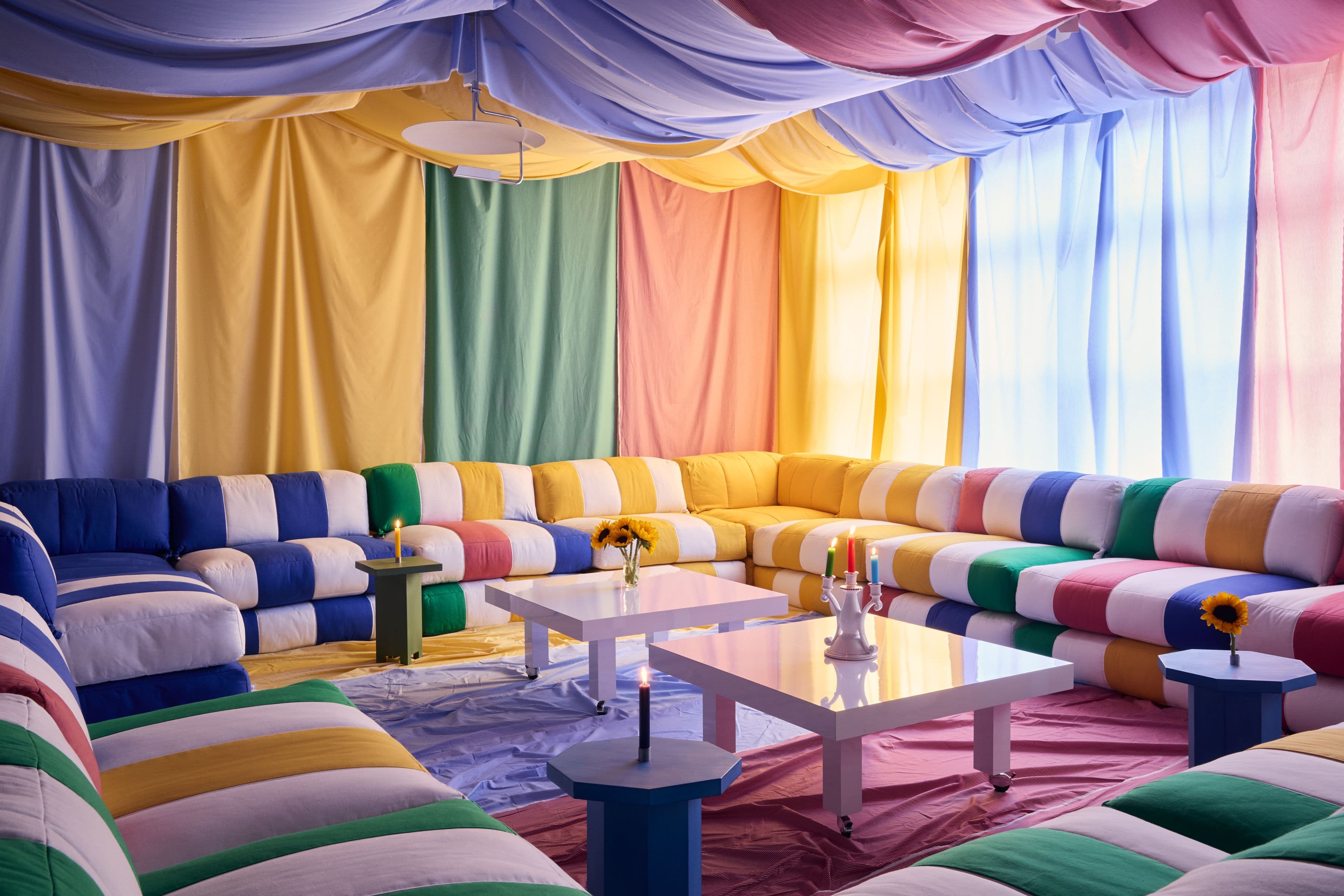 Multicolored striped Duvet System seating in a room draped with colorful textiles
