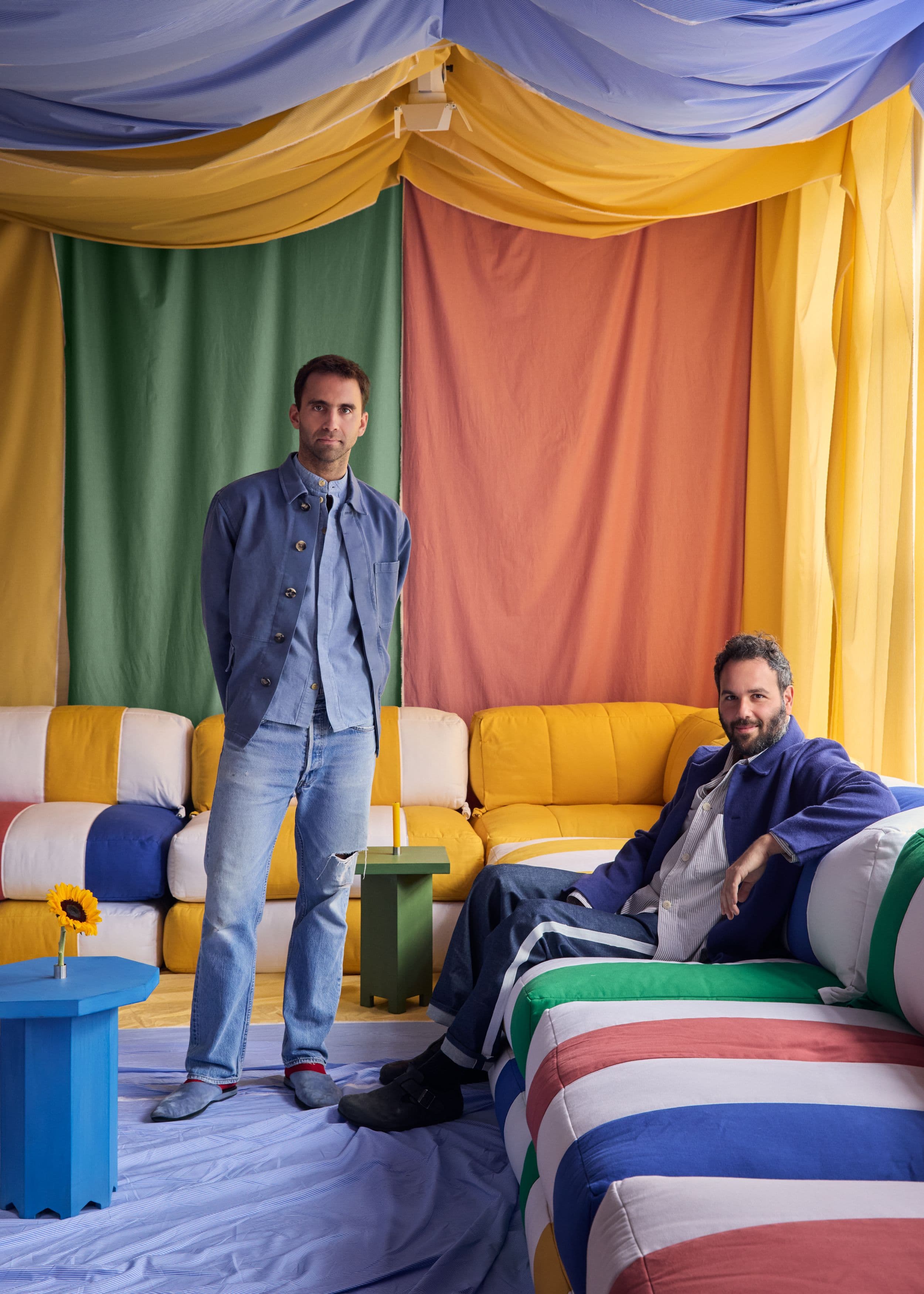 Will and Nicholas with the Duvet System, surrounded by colorful fabric draping and striped upholstered seating