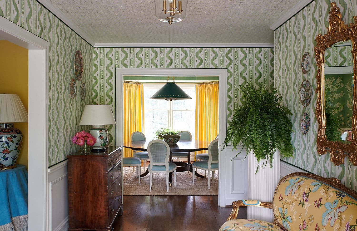 Mustard dining room drapery, upholstered dining chairs, and vibrant foreground settee