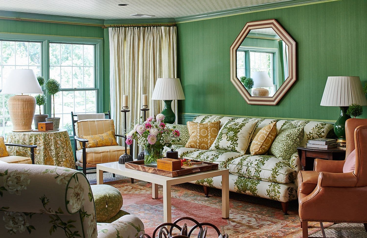Large upholstered floral sofa with custom pillows, and burnt orange leather chair